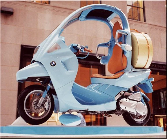 BMW C1 bleue exposée avec une selle en cuir et un top-case assorti.