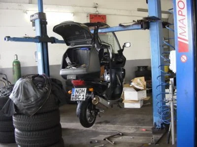 BMW C1 noire soulevée dans un atelier pour des opérations d’entretien.